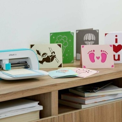 Máquina Cricut e cartões coloridos sobre móvel de madeira