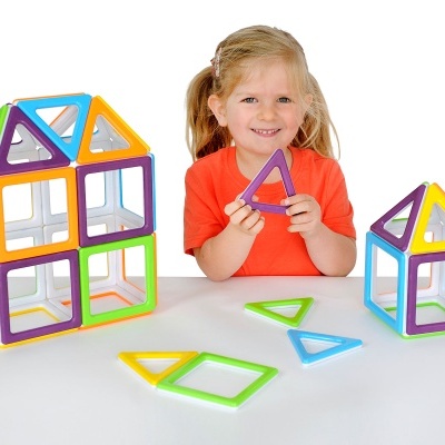 Brinquedo magnético colorido para crianças com formas geométricas e criança sorridente atrás.