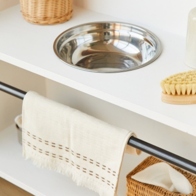 Lavatório redondo em aço inox, toalha creme pendurada e escova com cerdas perto