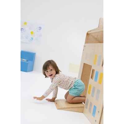 Criança a brincar numa estrutura de madeira colorida num espaço interior claro