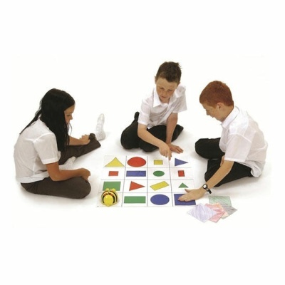 Crianças jogando jogo educativo com formas geométricas coloridas e cartas no chão