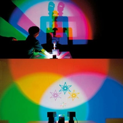 Criança cria sombras coloridas com dispositivo de luz num fundo branco