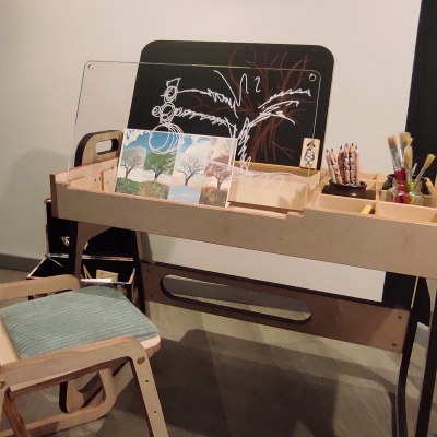 Mesa de atividades em madeira clara com tampo transparente e cadeira