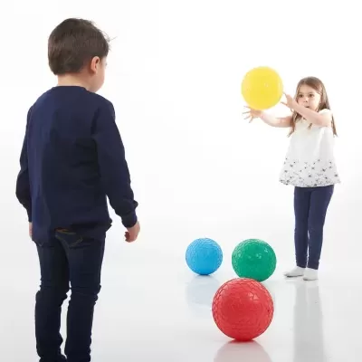 Duas crianças a jogar com bolas coloridas num fundo branco