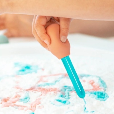 Criança segurando ferramenta plástica para desenhar em superfície texturizada colorida