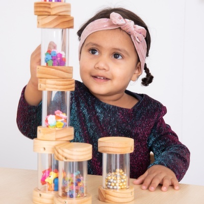 Criança brincando com tubos transparentes e tampas de madeira