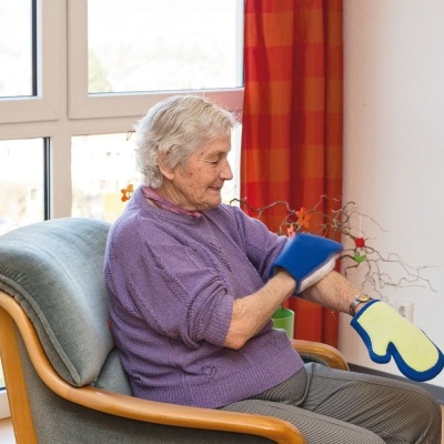 Mulher idosa sentada numa cadeira a usar suporte de braço azul e amarelo