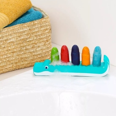 Brinquedo de banho de crocodilo azul com cilindros coloridos na banheira e cesta com toalhas