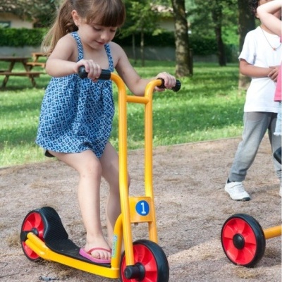 Criança a andar de trotinete amarela com rodas vermelhas e número 1 azul num parque