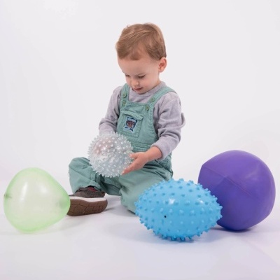 Criança com bolas coloridas pontiagudas e lisas