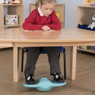 Criança sentada numa cadeira a usar brinquedo azul para pés sob mesa de madeira