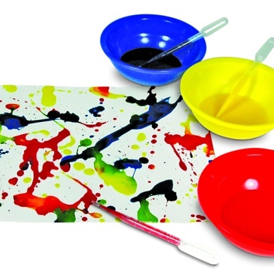 Três tigelas coloridas, colheres, pincel e folha com manchas coloridas