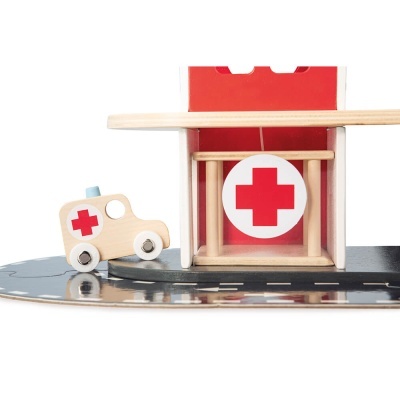 Brinquedo ambulância de madeira com cruz vermelha ao lado de edifício de brinquedo
