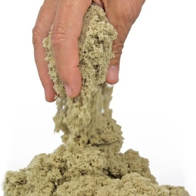 Mão a segurar e deixar cair areia cinzenta clara e granulada