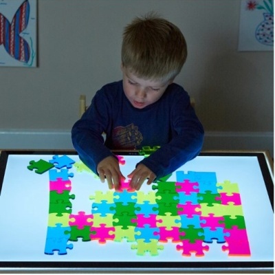 Criança a montar puzzle colorido numa superfície iluminada
