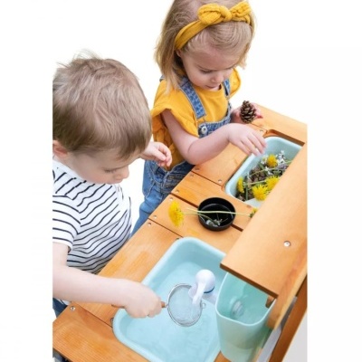 Crianças a brincar numa cozinha de brincar com água e flores