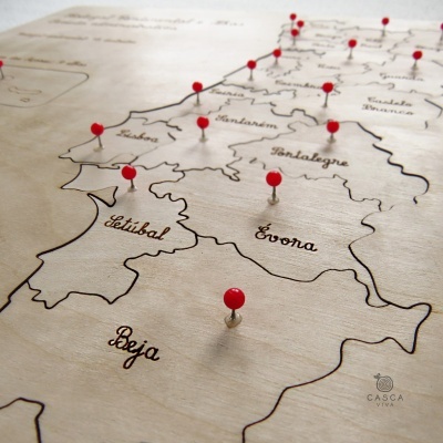 Mapa de Portugal em madeira com alfinetes vermelhos marcando várias regiões