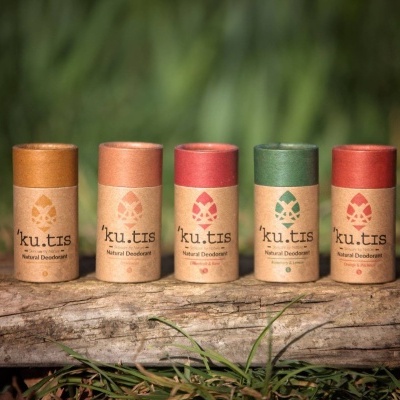Desodorizantes naturais Ku.tis em embalagens recicladas com tampas coloridas sobre um tronco