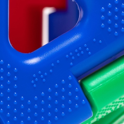 Detalhe de brinquedo infantil colorido em plástico com texturas pontilhadas.