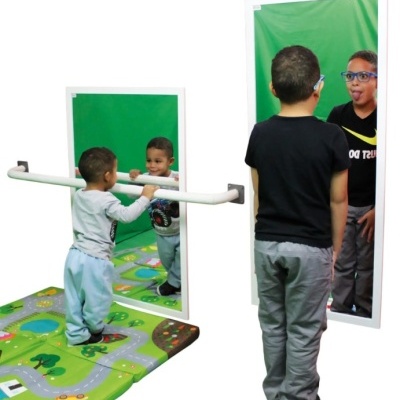 Espelho de parede com barra de apoio e duas crianças refletidas em fundo verde