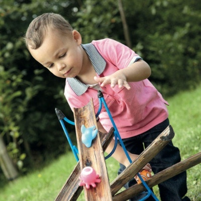 Criança a brincar com brinquedo de madeira e peças de plástico ao ar livre