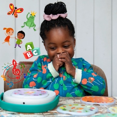 Criança com pijama azul a brincar com brinquedo educativo e cartões redondos coloridos