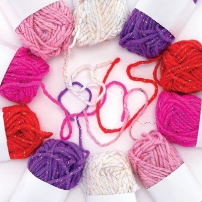 Oito novelos de lã coloridos em disposição circular sobre fundo branco