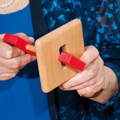 Dispositivo de madeira quadrada com varas vermelhas nas mãos de pessoa vestindo azul