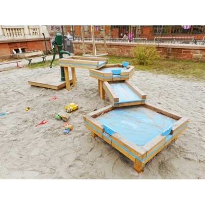 Estrutura de madeira com bandejas azuis em zona de areia exterior