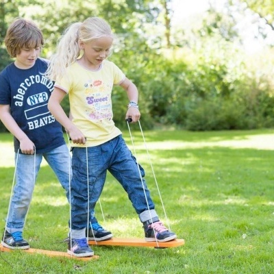 Crianças a brincar com brinquedo de madeira no jardim