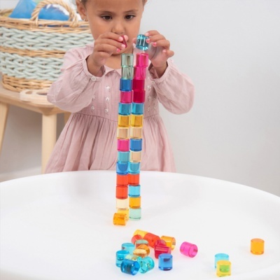 Criança a empilhar blocos de plástico colorido numa mesa branca
