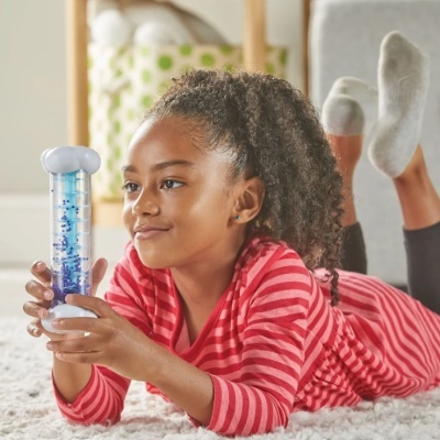 Menina de vestuário vermelho de riscas segurando brinquedo cilíndrico com bolas azuis