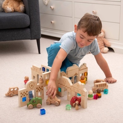 Menino a brincar com brinquedos de construção de madeira coloridos