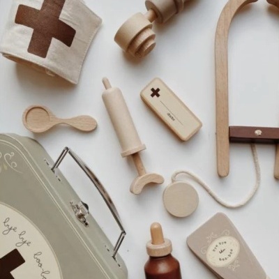 Brinquedos médicos em madeira e tecido com mala hospitalar cinza e detalhes castanhos
