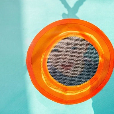 Criança olhando através de janela de rede circular em estrutura azul e laranja