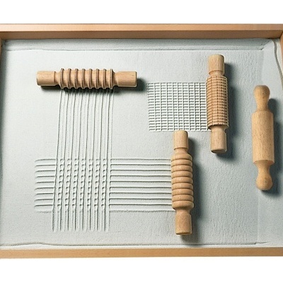 Tabuleiro com areia branca e três rolos de madeira texturizados