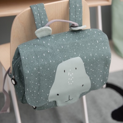 Mochila infantil verde com rosto de animal e orelhas pendurada em cadeira de madeira