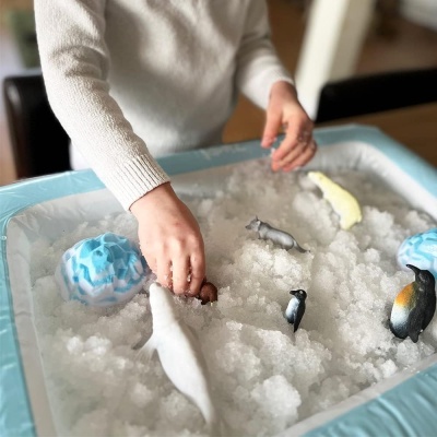 Criança a brincar com tabuleiro de gelo e figuras de animais de plástico