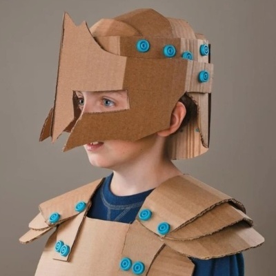 Criança com capacete e armadura de cartão castanho com botões azuis