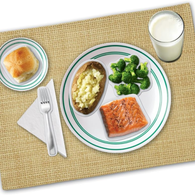 Refeição servida num prato com salmão, brócolos, batata, pão, copo de leite e talheres sobre tapete bege