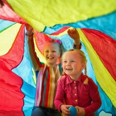 crianças brincando sob tecido colorido com bolas