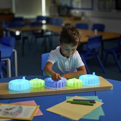 Criança a brincar com brinquedos de flores translúcidas azuis, amarelas e lilás que brilham