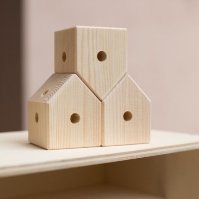 Três blocos de madeira em forma de casinhas empilhadas.