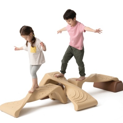 Crianças brincando em brinquedos de equilíbrio de plástico bege e castanho com texturas onduladas em fundo branco