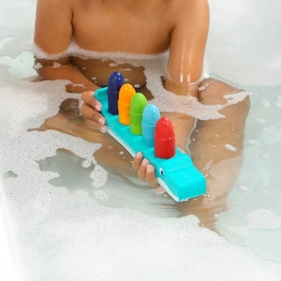 Brinquedo de banho colorido em forma de crocodilo azul na banheira com espuma