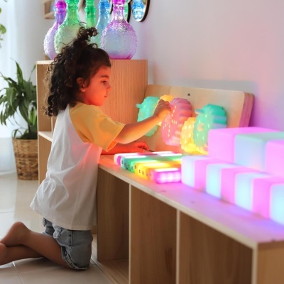 Criança a brincar com brinquedos LED coloridos sobre móvel de madeira
