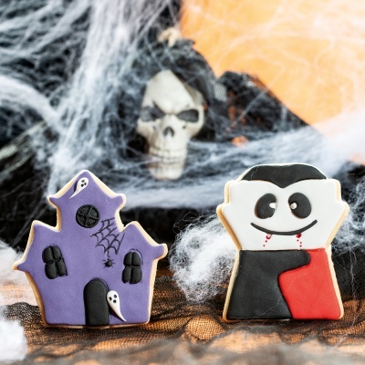 Biscoitos decorados de Halloween, casa assombrada e vampiro, sobre teias de aranha e caveira decorativa