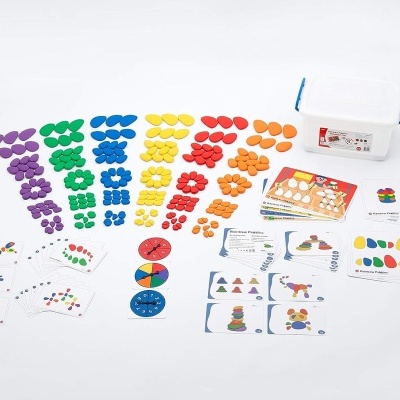Conjunto educativo colorido com peças de plástico e cartões, em recipiente branco com tampa azul.