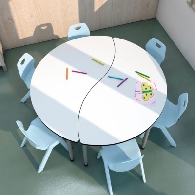Mesa redonda branca com cadeiras azuis e lápis de cores sobre ela