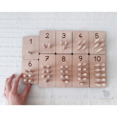 Peças de madeira numeradas com pinos para contagem sobre tecido branco